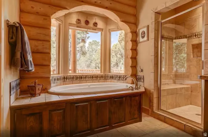 Primary bathroom with built-in jetted tub with tile surround, wood-paneled base, and bay window
