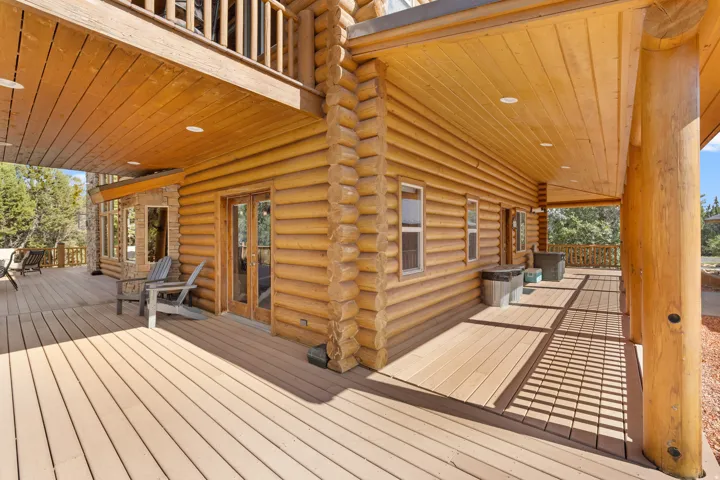 Expansive wood-finish decking, log-style exterior construction, natural wood ceiling, recessed lighting, and double glass-panel doors