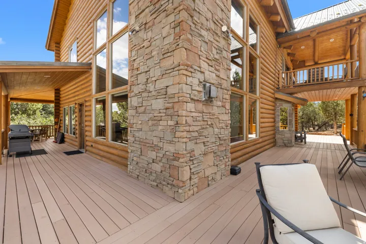 Expansive deck with composite decking, a stone-clad exterior wall, a covered porch, and large windows
