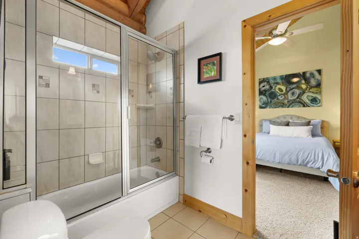 Jack and Jill bathroom with tub, a glass enclosure, tile surround, and a high transom window