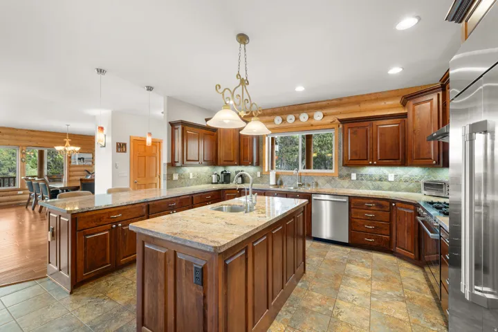 Kitchen featuring wood cabinetry, stone countertops, a central island, stainless steel appliances, and tile flooring