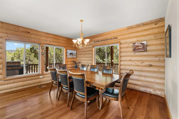 Dining room with log interior walls and a wood-finish floor