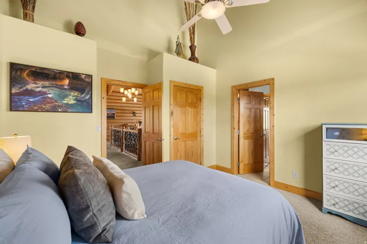 Bedroom 3 with vaulted ceiling, ceiling fan, solid wood doors, wood trim, and carpeted flooring