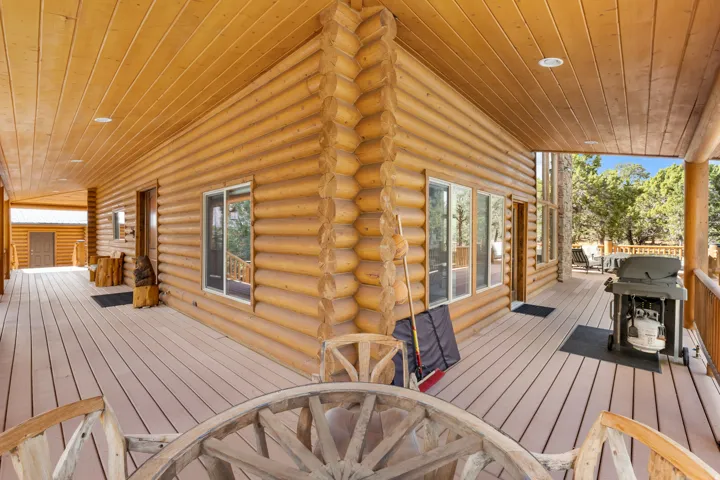 Expansive wrap-around porch with a wood-finish ceiling, log exterior, and a durable composite deck
