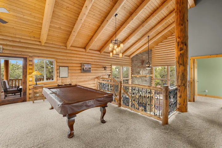 Vaulted wood-plank ceilings, log wall construction, and a stone fireplace