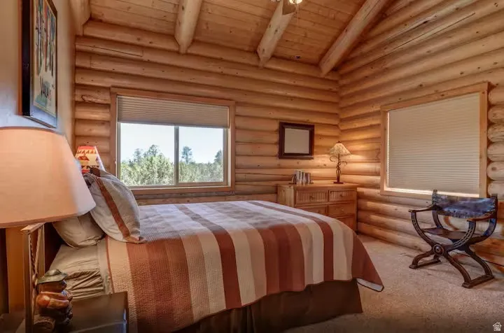 Bedroom 4 with wood-paneled walls and exposed wood beam vaulted ceiling