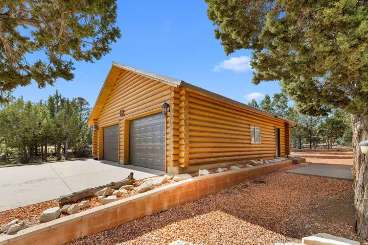Log cabin style detached garage featuring two roll-up doors, an exterior wall light fixture, and a window