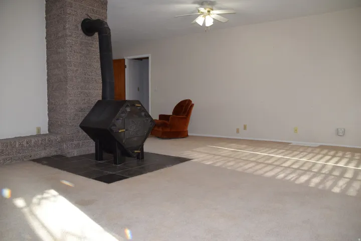 Brick fireplace with a wood-burning stove, tile hearth, and carpeted flooring