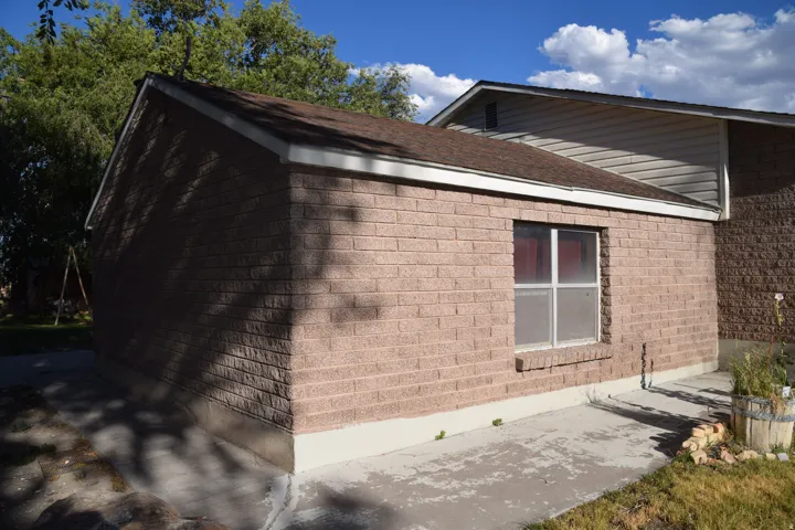 Brick exterior residence featuring a modern concrete entry pad, large fixed window with contemporary framing, and clean architectural lines