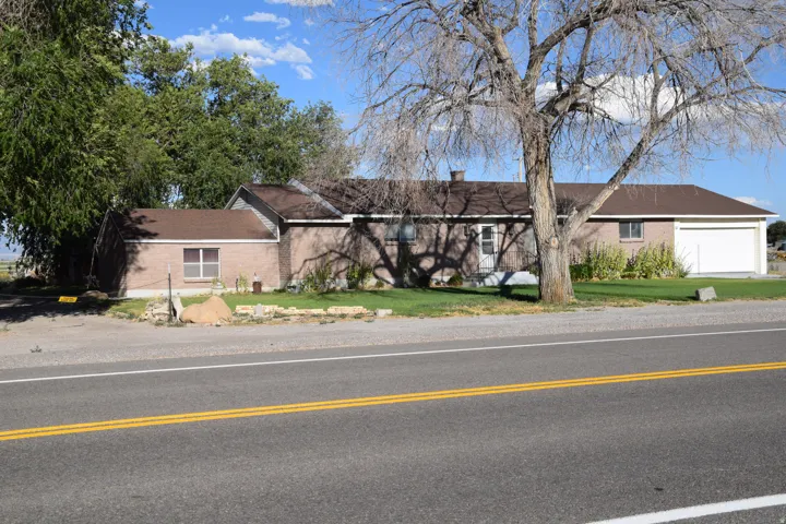 Single-story residence featuring a brick exterior, brown shingle roofing, attached two-car garage, and mature trees on the property