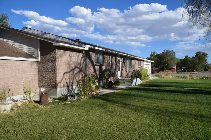 Brick exterior with white trim, concrete steps with metal railing, attached garage, and a lush green lawn