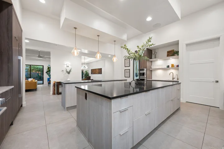 Kitchen featuring two islands, integrated appliances, recessed lighting, pendant lighting, and light-toned tile flooring