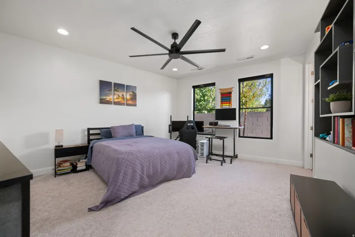 Recessed lighting, ceiling fan, built-in shelving, and two windows with black trim
