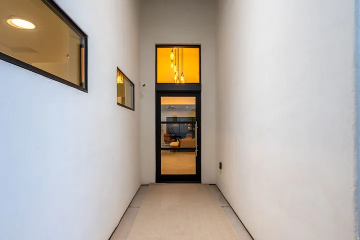 White stucco exterior with multiple fixed windows and a glass-paneled entry door