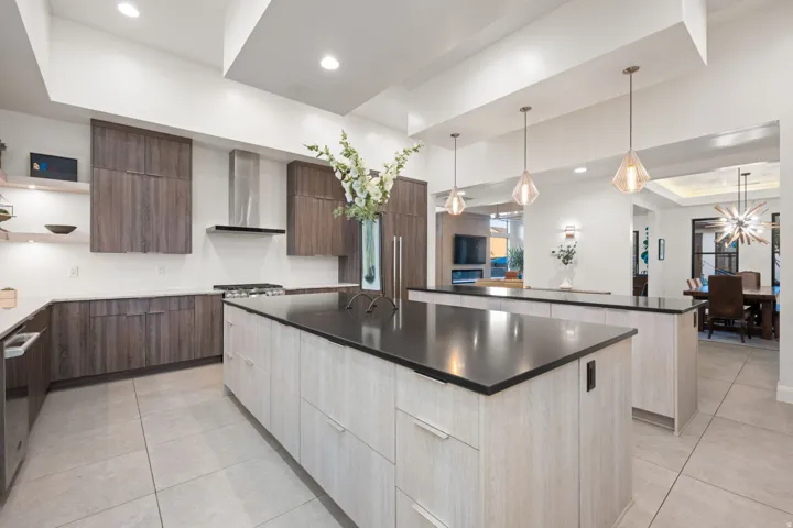 Gourmet kitchen featuring dual islands with dark countertops, wood-finish cabinetry, stainless steel appliances, and recessed lighting
