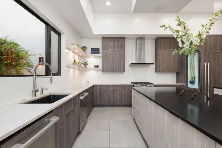 Contemporary kitchen with wood-finish cabinetry, light-toned countertops, a contrasting dark island countertop, stainless steel appliances, and recessed lighting