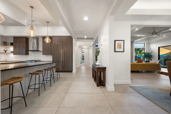 Gourmet kitchen featuring dark wood-finish cabinetry, stainless steel appliances, and two geometric pendant lights above the island
