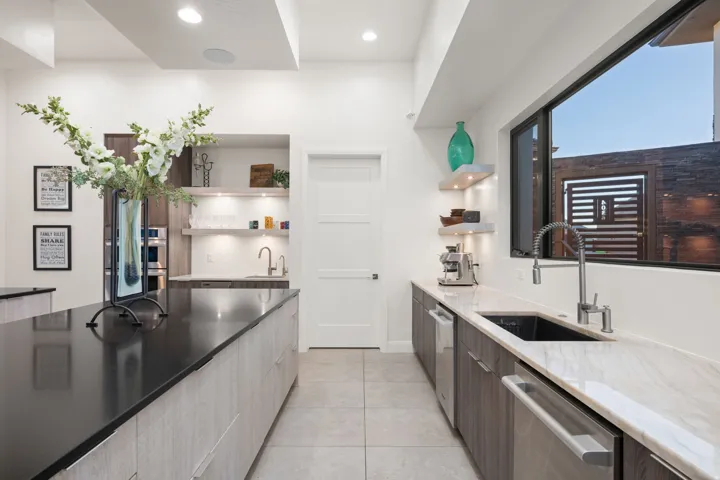 Spacious kitchen featuring a large island with a dark countertop, light-toned cabinetry, stainless steel appliances, and an undermount sink