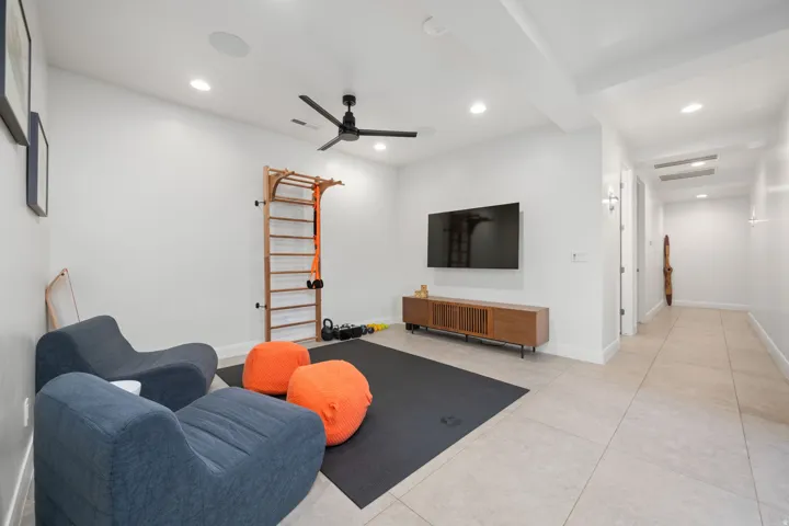 Recessed lighting, ceiling-mounted speakers, and a ceiling fan enhance this versatile space