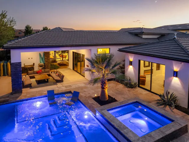 Expansive outdoor living area featuring a swimming pool with integrated spa, covered patio, and tile roofing