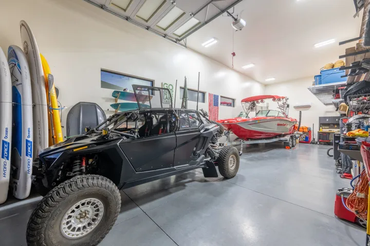 Spacious garage with high ceilings, multiple overhead light fixtures, and a smooth concrete floor