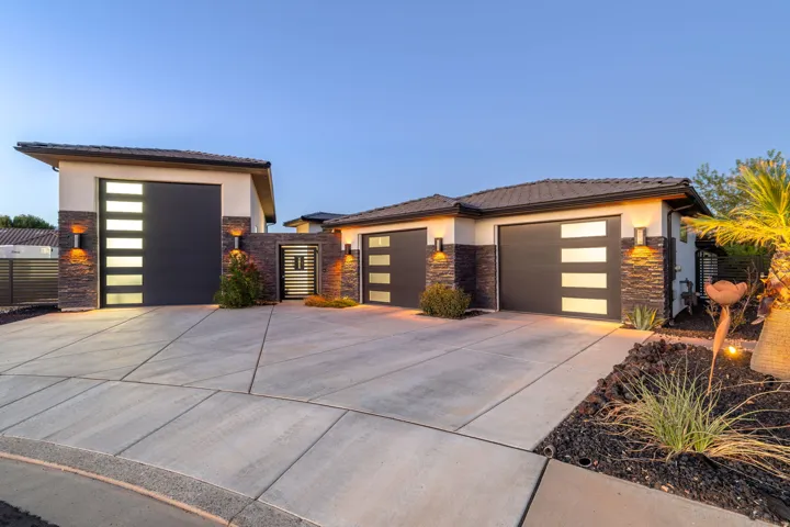 Contemporary exterior featuring multiple garage doors with frosted glass panels, stone accents, and a concrete driveway