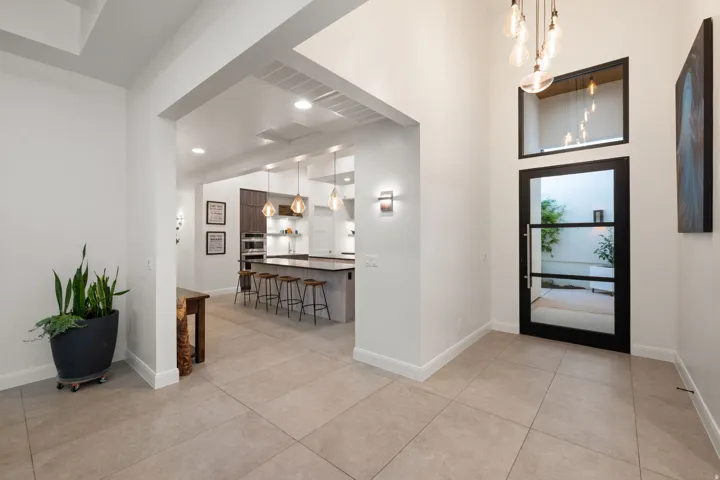 Tiled flooring, high ceilings, recessed lighting, modern pendant lighting, and a contemporary glass-paneled entry door