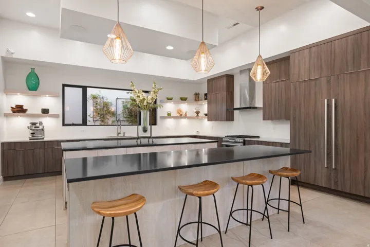 Spacious kitchen featuring an expansive island, wood-finish cabinetry, built-in appliances, and recessed lighting