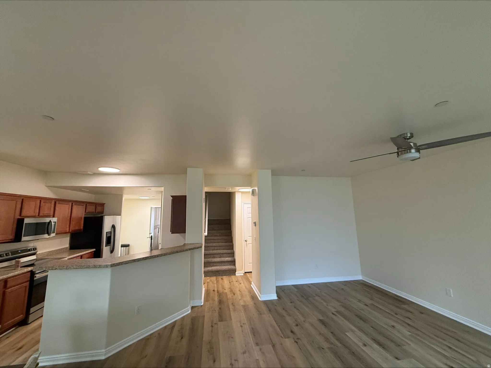 Open-concept living space with wood-finish flooring, a ceiling fan, and recessed lighting