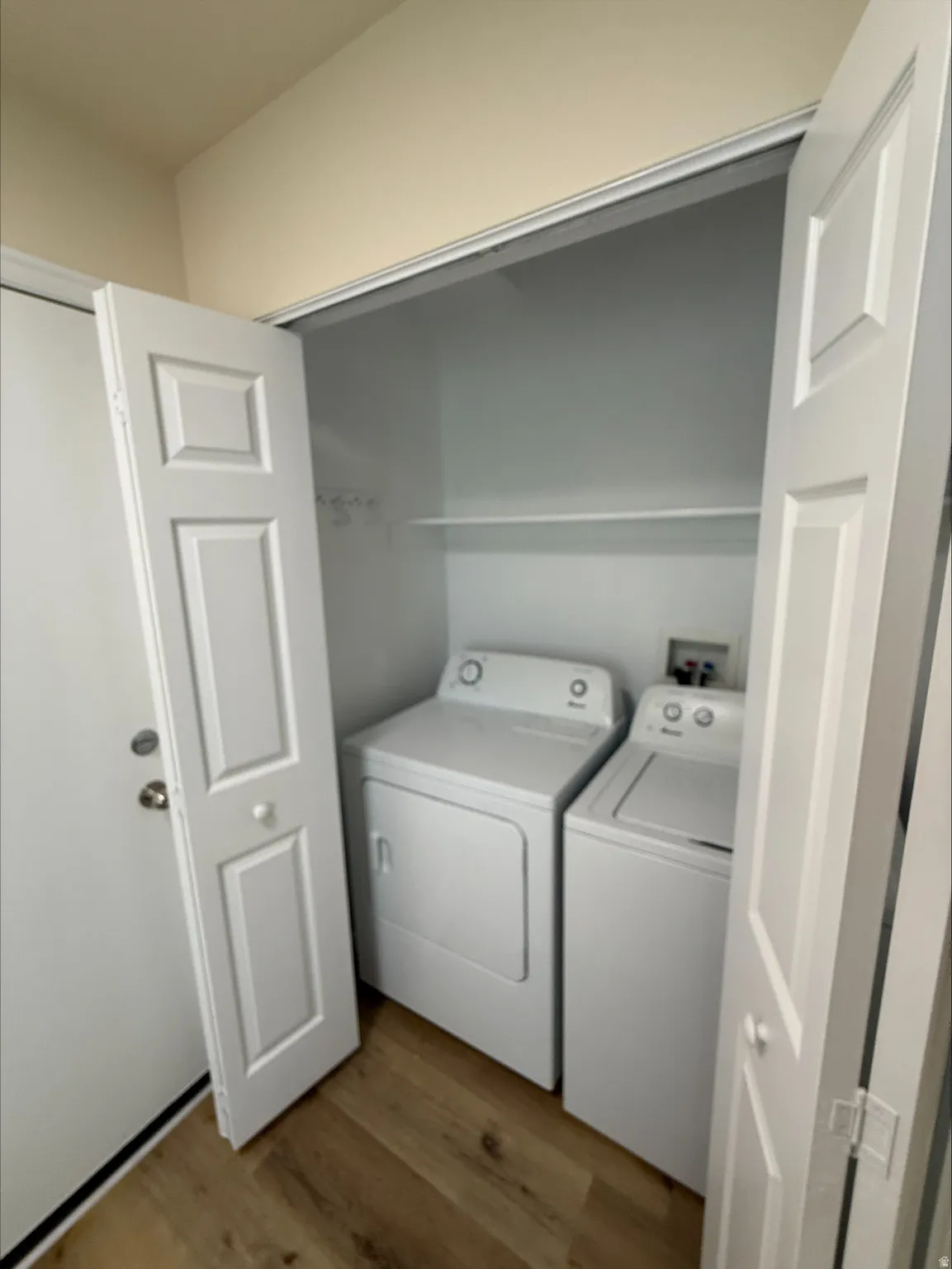 Laundry area with a built-in shelf, wood-finish flooring, and panel bi-fold doors