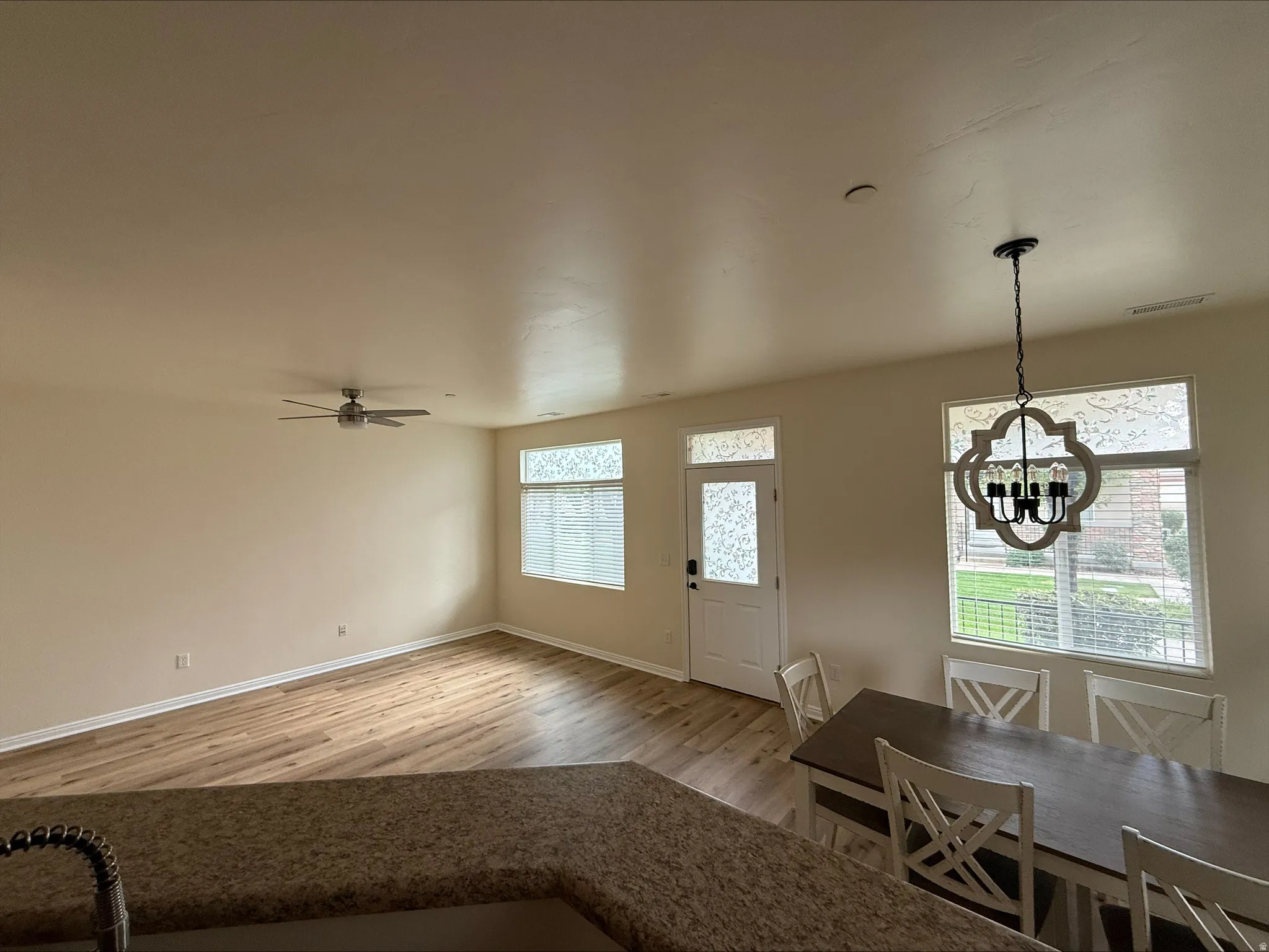 Open concept living area with wood-finish flooring, a ceiling fan, and a decorative chandelier