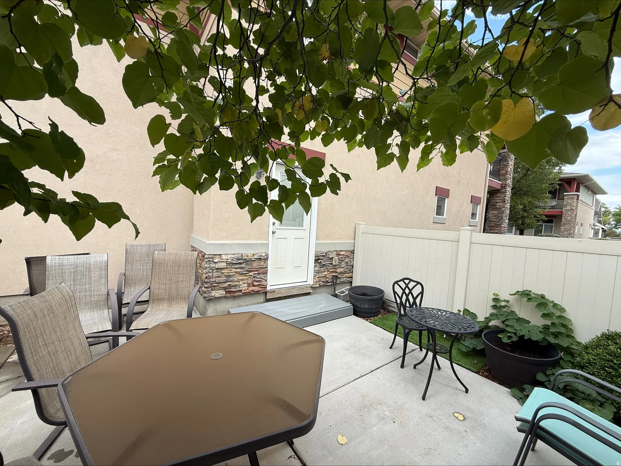 Private patio with concrete surfacing, a privacy fence, and a stone veneer accent wall