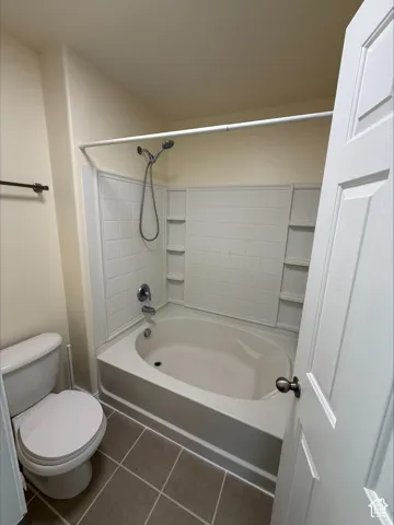 Tub and shower combination with a curved basin, integrated shelving, and a handheld showerhead
