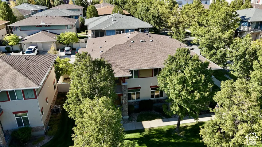 Two-story residence with a multi-gabled roof, featuring mature trees and a paved walkway