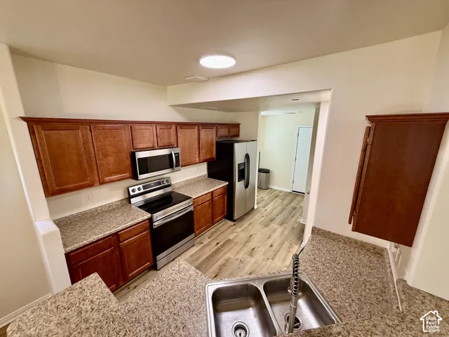 Wood-finish flooring throughout, complete with a double basin stainless steel sink and a stainless steel appliance suite