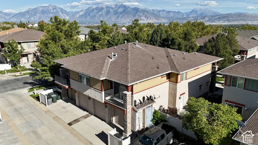 Multi-level residence featuring a brown shingle roof and a light-colored stucco exterior