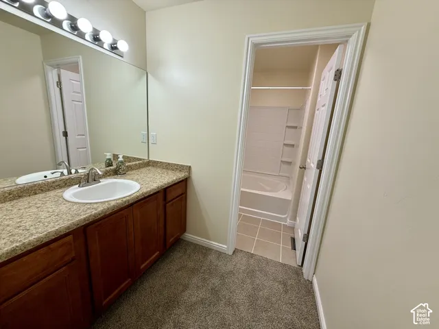 Vanity with a laminate countertop and an integrated sink, illuminated by a strip light fixture, and a full-width mirror