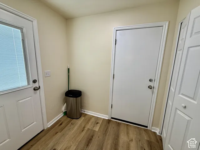 Wood-finish flooring, white paneled doors, white trim, and neutral wall paint