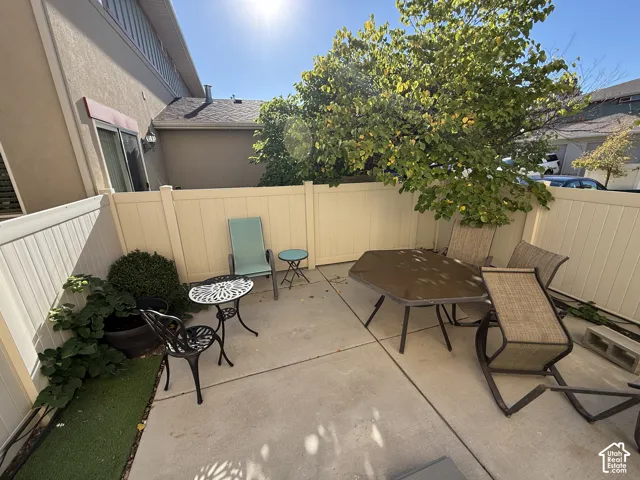 Private concrete patio space with privacy fencing, shrubbery, and mature trees