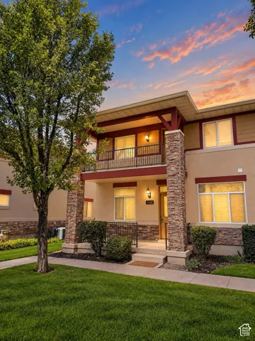 Contemporary exterior with stacked stone accents, a covered front entry, and a second-story balcony with metal railing
