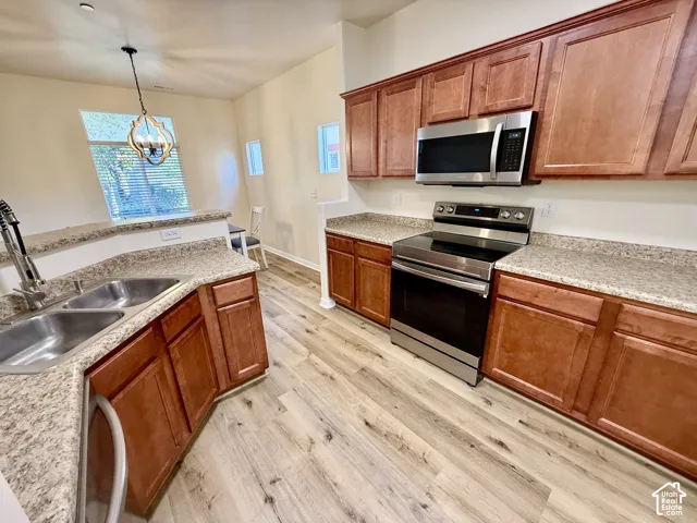 Kitchen featuring wood-finish flooring, stainless steel appliances, granite-style countertops, and wood cabinetry