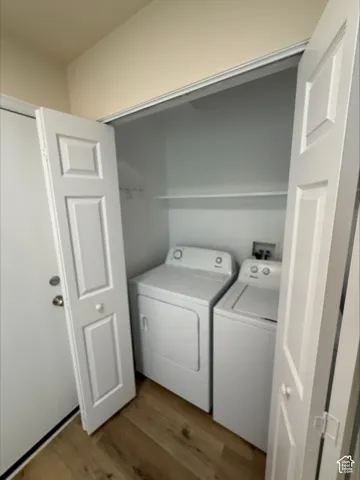 Laundry area with a built-in shelf, wood-finish flooring, and panel bi-fold doors