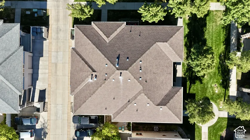 Pitched roofline with multiple gables, surrounded by mature trees and paved walkways