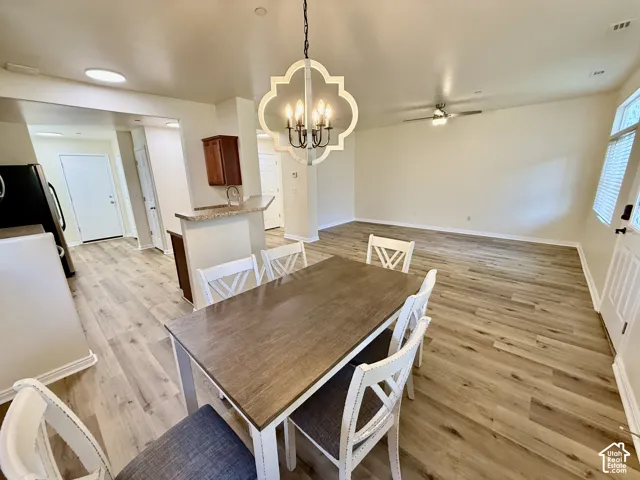 Open-concept living area with wood-finish flooring, a contemporary chandelier, and a ceiling fan