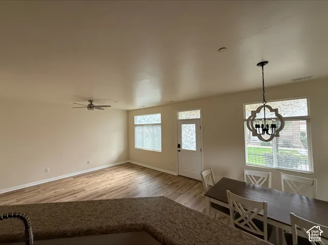 Open concept living area with wood-finish flooring, a ceiling fan, and a decorative chandelier