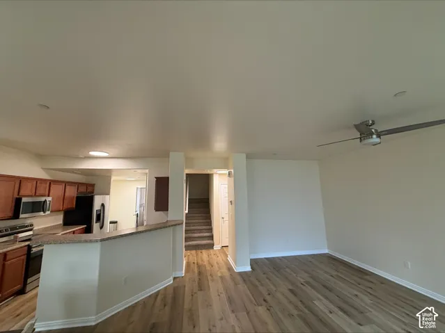 Open-concept living space with wood-finish flooring, a ceiling fan, and recessed lighting