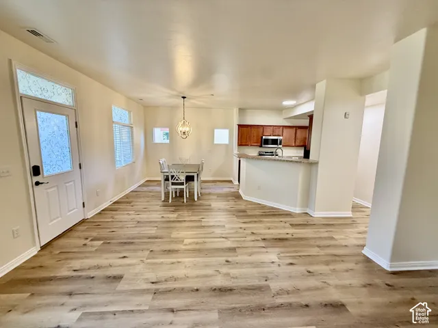 Open-concept layout featuring wood-finish flooring, a kitchen with wood cabinetry, and a breakfast bar