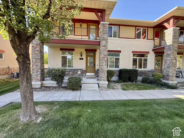 Stucco exterior with stone veneer accents, multi-level design, and upper-level balconies with wrought iron railings