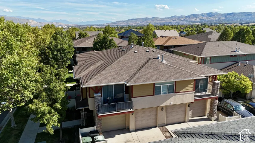 Multi-level property featuring a multi-car garage, upper balcony with metal railing, and a stone facade column