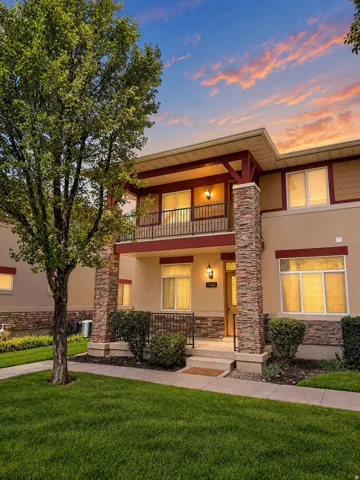 Contemporary exterior with stacked stone accents, a covered front entry, and a second-story balcony with metal railing